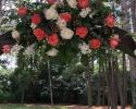 Coral and white wedding flowers for a rustic wooden arch at The Springs Event Venue.