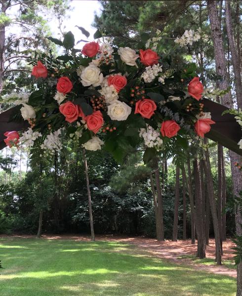 Coral and white wedding flowers for a rustic wooden arch at The Springs Event Venue.
