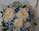 Creme roses, blue delphinium, white button mums and baby's breath, nestled in a blue and silver wire nest, accented with blue jewels and greenery