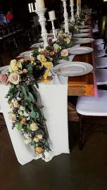 Luxurious table runner full of roses, spray roses, and babies breath. 