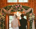 An assortment for pinks, cremes, green flowers accent this wooden arch