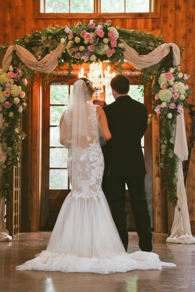 An assortment for pinks, cremes, green flowers accent this wooden arch